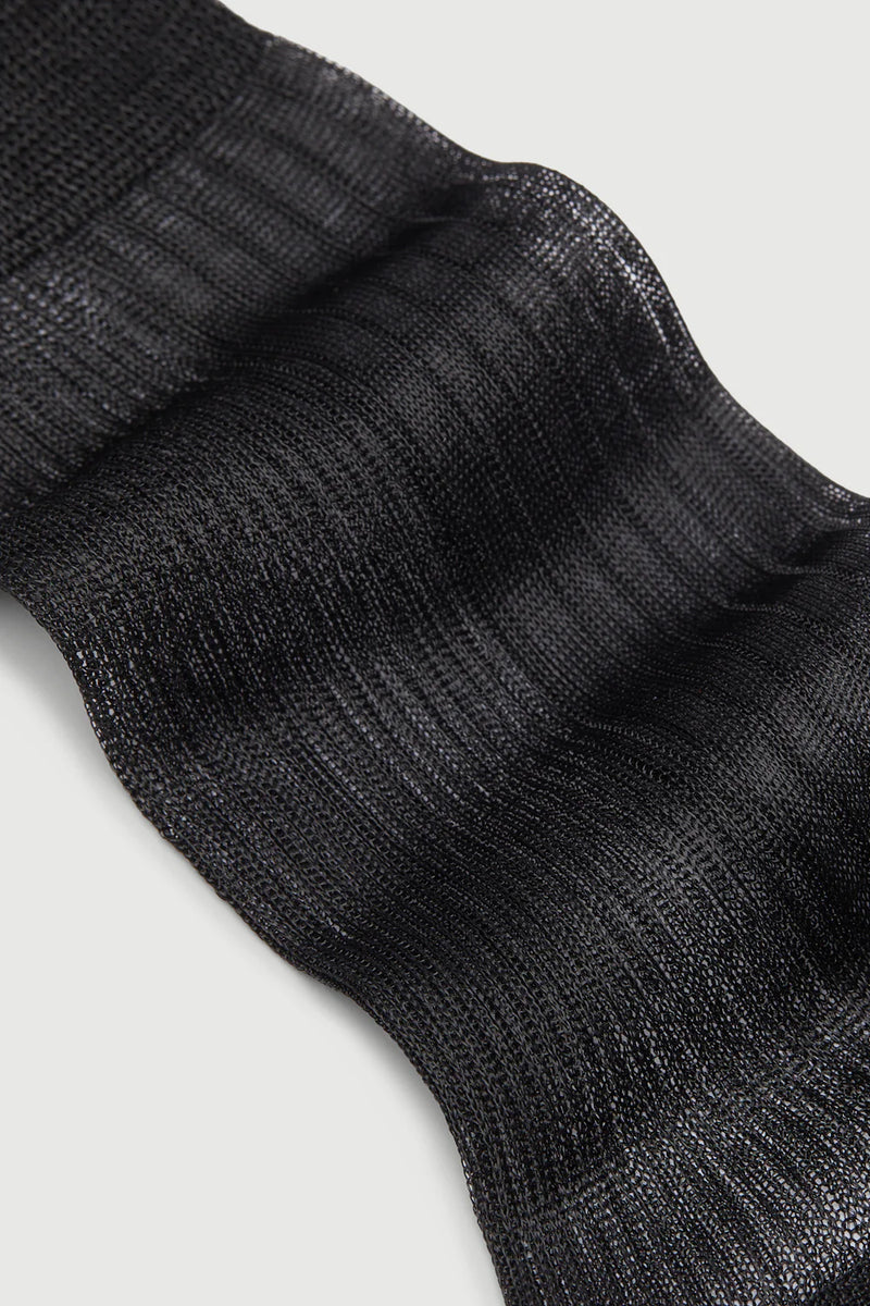 Close-up of a black sock with ribbed texture on a light gray background