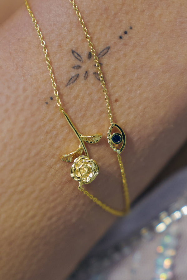 Gold bracelet with rose and eye design on wrist