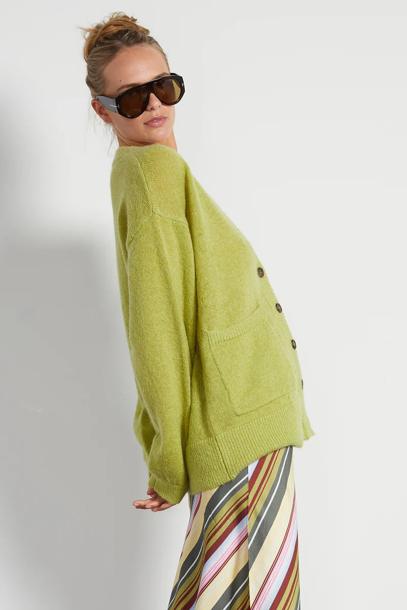 Person wearing a green sweater and sunglasses on a plain background