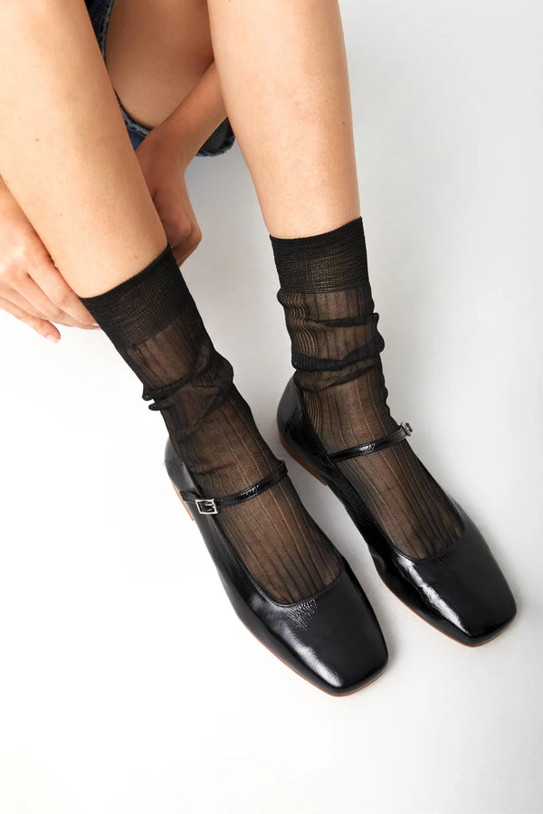 Black shoes with sheer socks on a white background