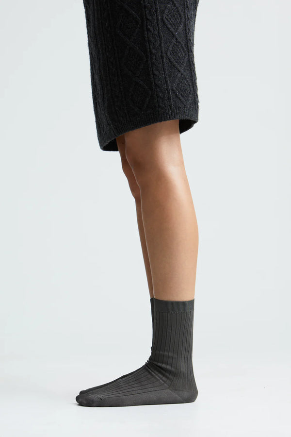 Person wearing dark gray socks with a plain background