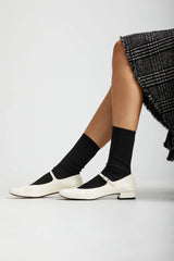 White shoes, black socks, and a black patterned skirt on a white background