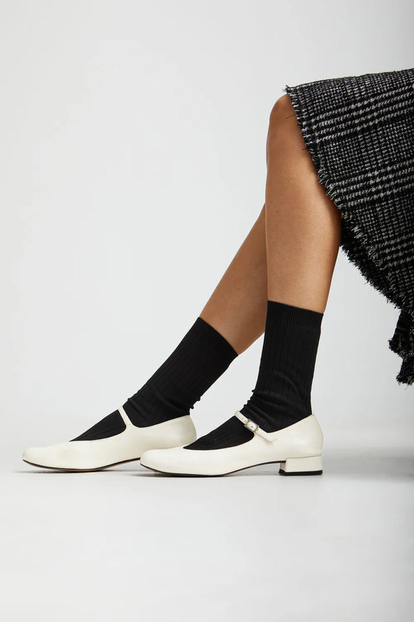 White shoes, black socks, and a black patterned skirt on a white background