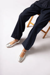 Navy striped pants and silver flats on a white background