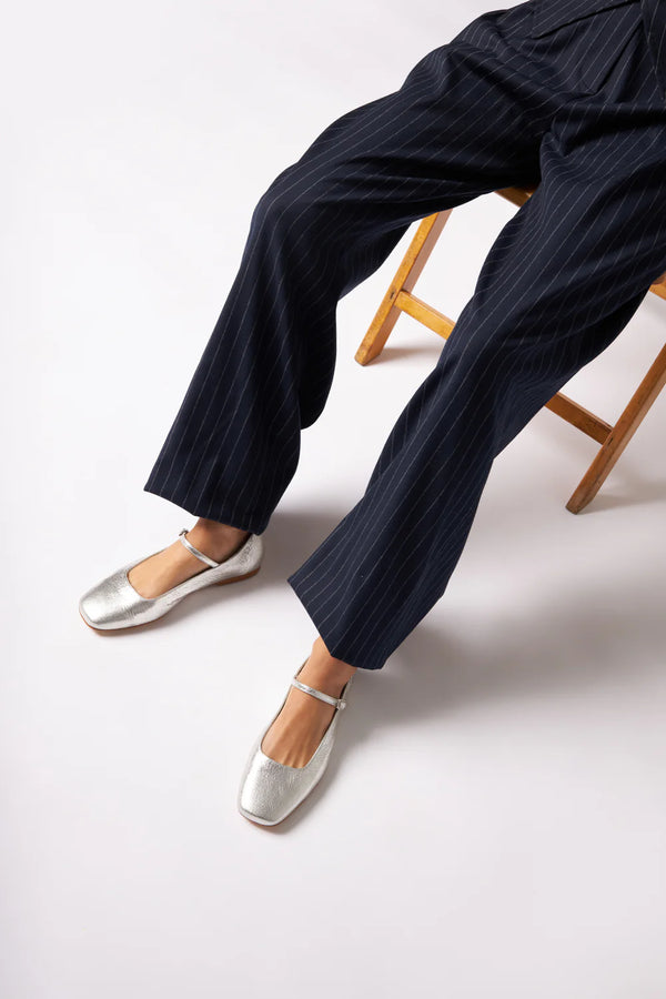 Navy striped pants and silver flats on a white background