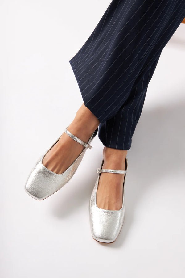 Silver flats worn with navy pinstripe pants on a white background