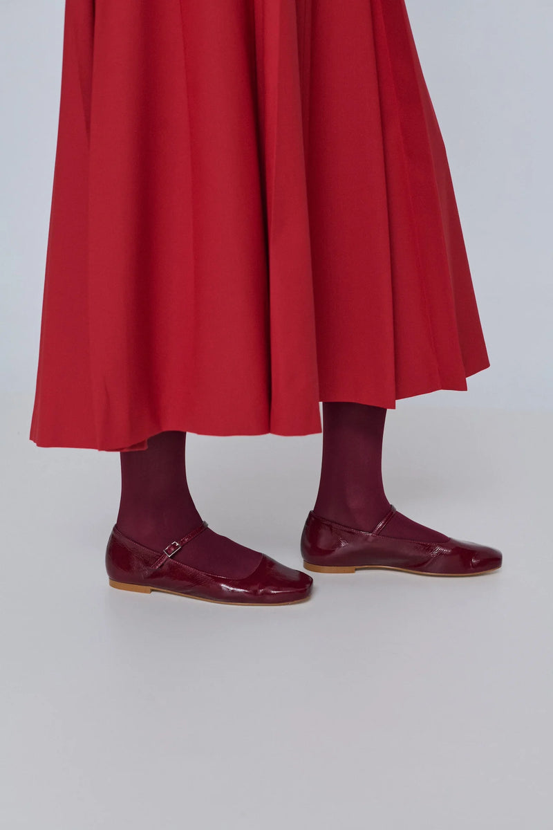 Person wearing a red skirt and maroon shoes on a white background