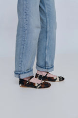 Person wearing leopard print sandals and blue jeans on a plain background