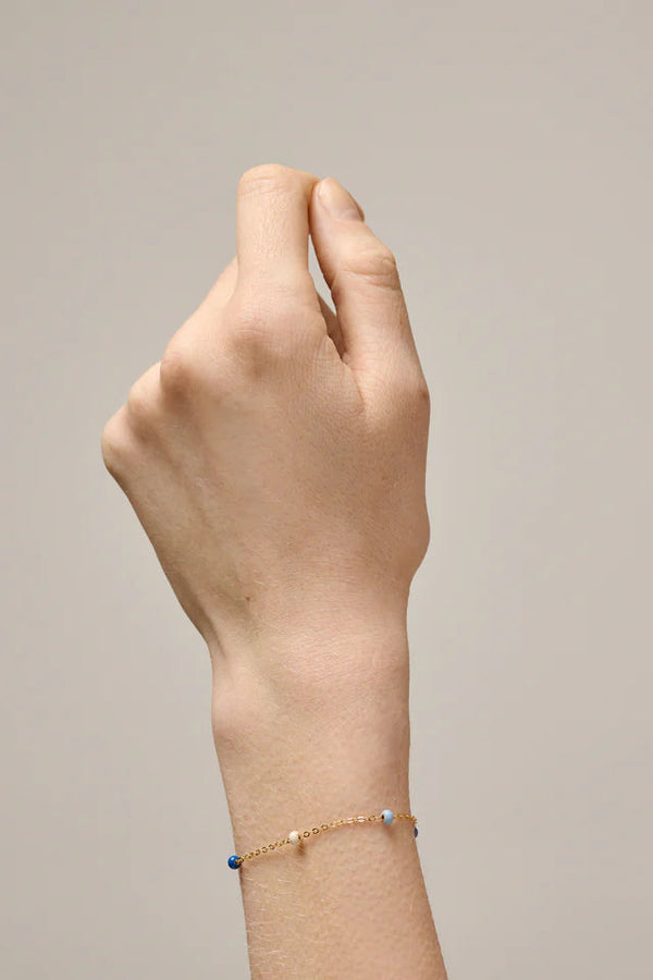 Hand wearing a bracelet on a plain background