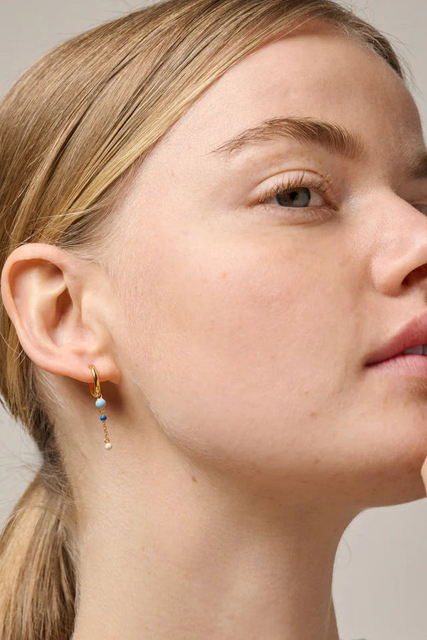 Close-up of a woman wearing a gold earring with small beads.