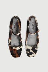 Pair of cow print flats on a white background