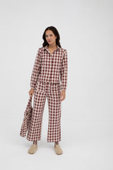 Woman wearing a red and white checkered jumpsuit on a white background