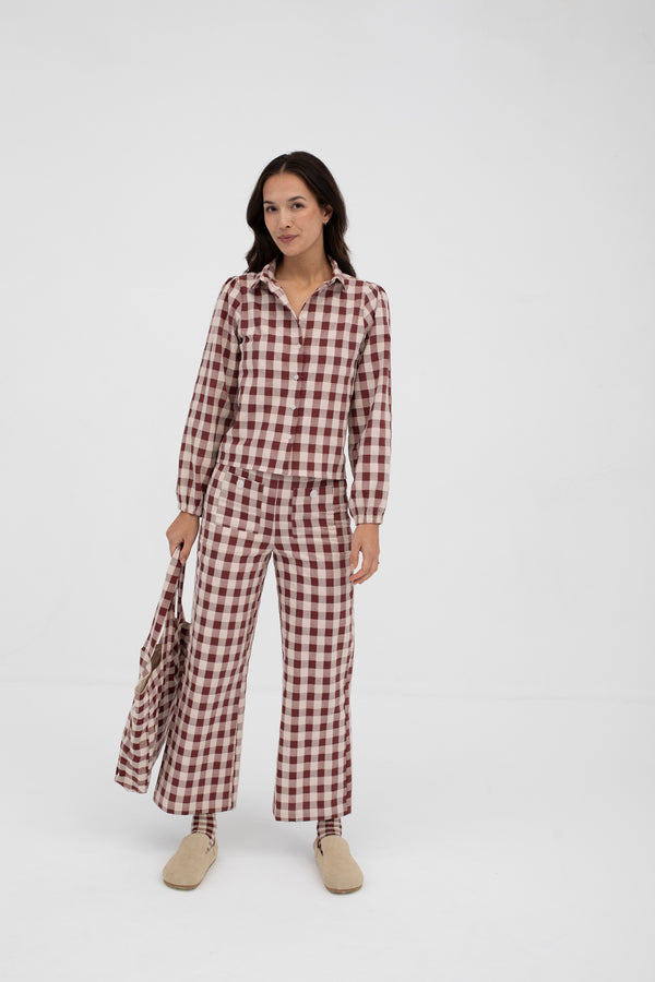 Woman wearing a red and white checkered jumpsuit on a white background