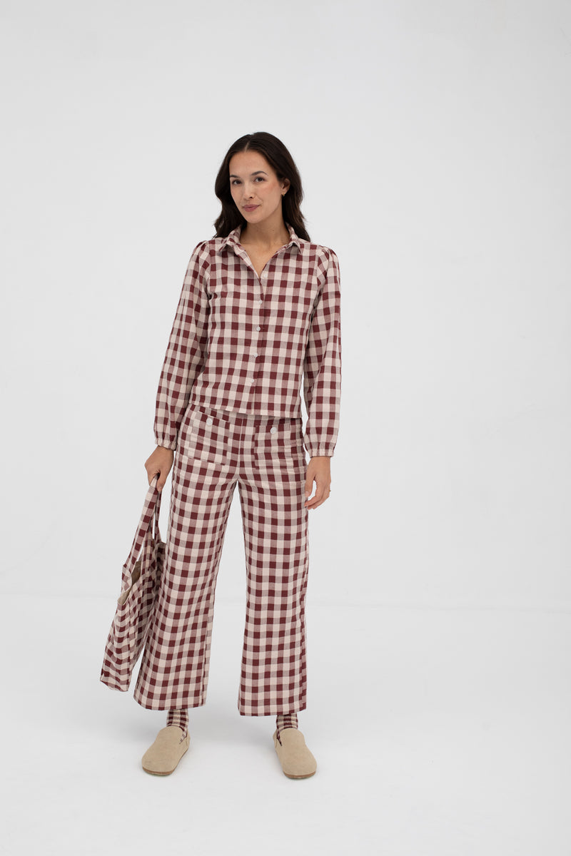 Woman wearing a red and white checkered jumpsuit on a white background