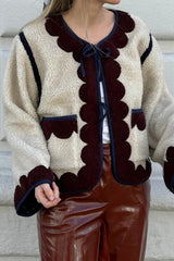 Person wearing a patterned cardigan with a plain background
