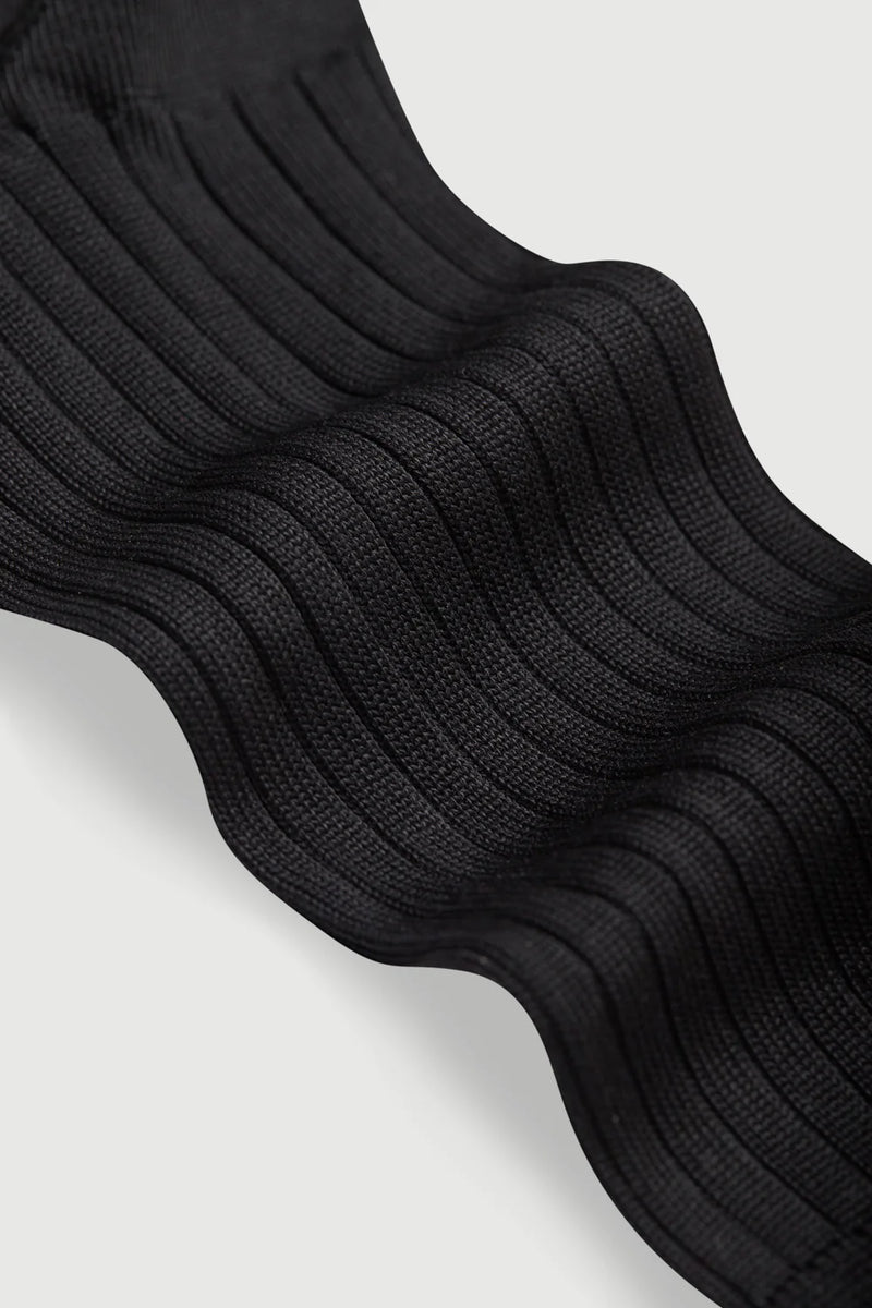 Stack of black socks on a light gray background
