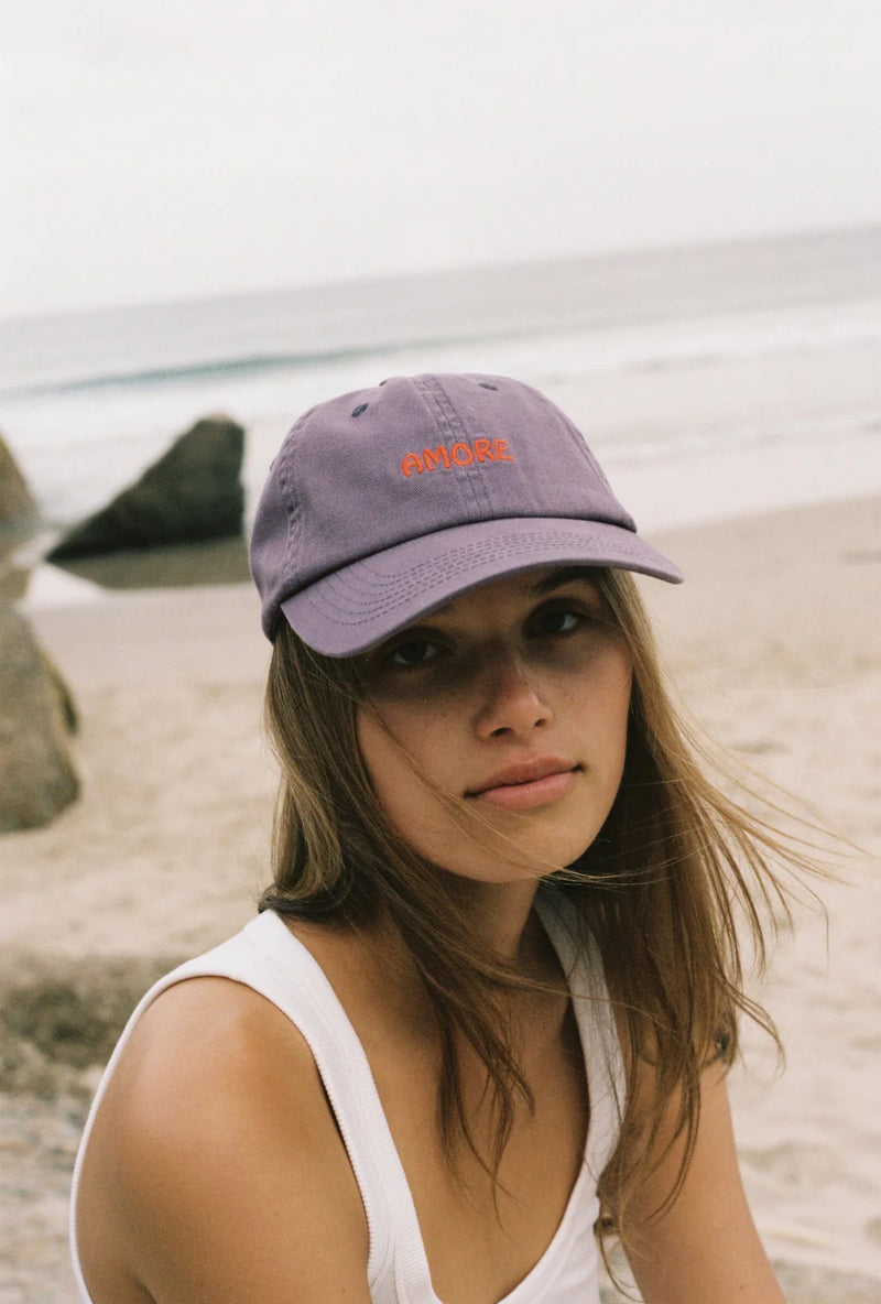 Woman wearing a purple cap with text on a beach